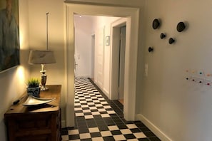 A hallway with a checkered floor, a lamp, and wall-mounted decorations. - Villa Hoyerberg Lake (Lindau)