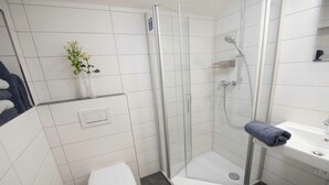 A modern bathroom with a glass-enclosed shower, a white toilet, a sink, and a small plant on the wall. - Holiday apartment with 1 bedroom (Oberkirch, Deutschland)
