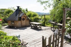 Eine Holzterrasse mit einer rustikalen Holzkonstruktion, einem Tisch und einer Bank.