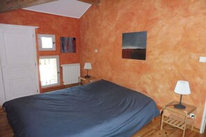 Ein Schlafzimmer mit einem Bett, zwei Nachttischlampen, einem Fenster und einer Tür.