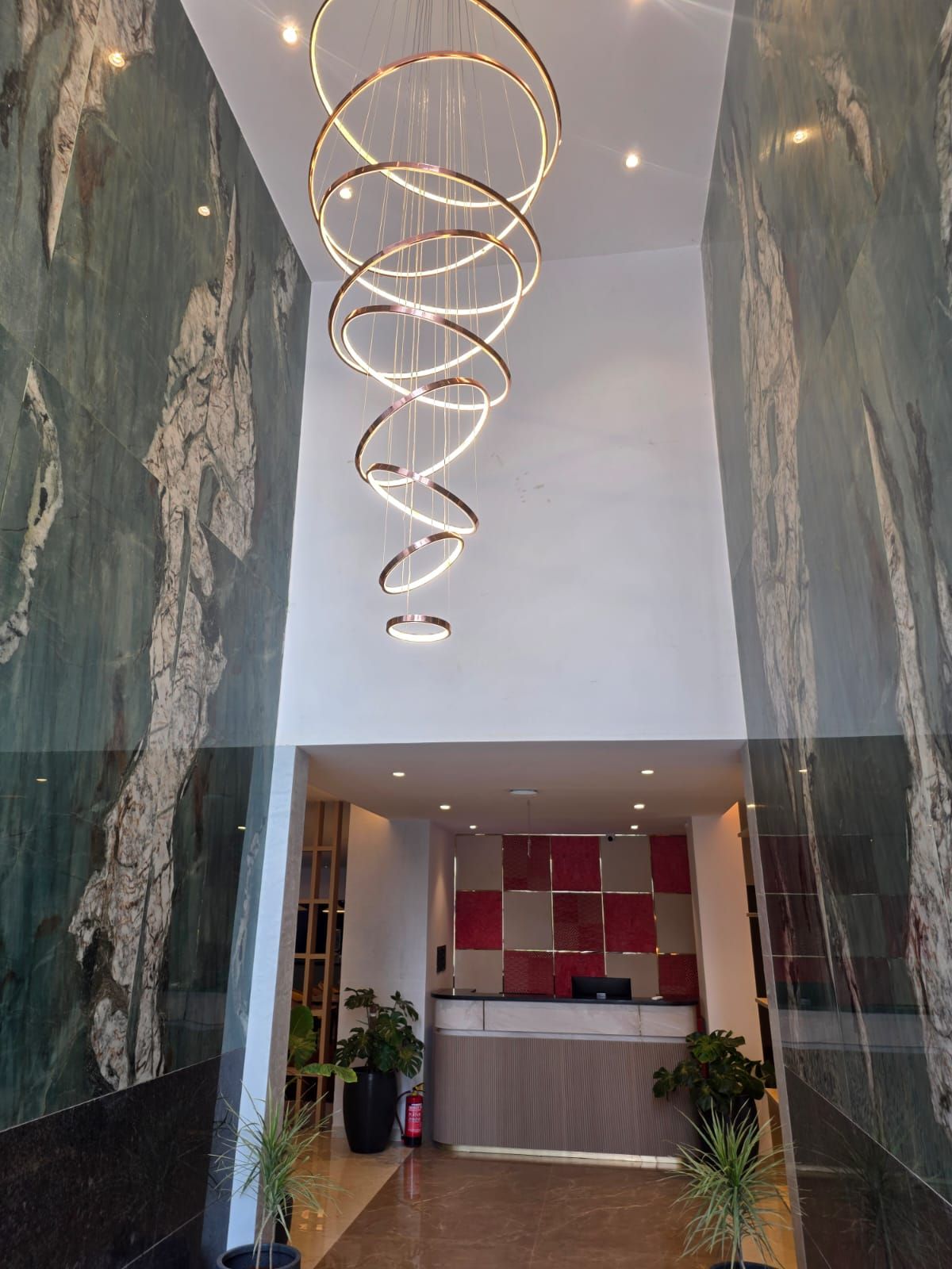 A modern reception area with a spiral light fixture, marble walls, and a reception desk.