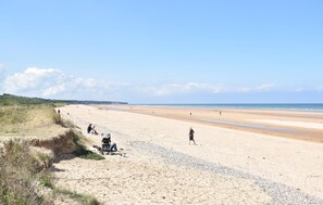 A wide sandy beach with a few people and a stroller, under a clear sky. - 3 bedroom cozy home in Creances (Creances)