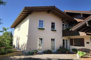 A two-story building with a sloped roof, multiple windows, and potted plants. - Holiday home in Andechs with swimming pool (Andechs)