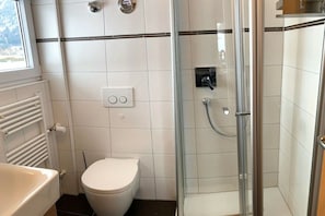 Casa de banho com sanita, cabine de duche e radiador.