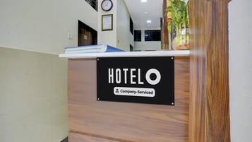 A reception desk with a sign that reads 'HOTEL O' and 'Company Serviced.'