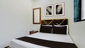 A bed with a black and white bedspread, a wooden headboard, and two framed artworks above it.