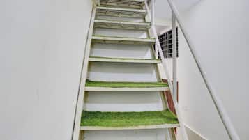 A staircase with white walls and green artificial grass steps.