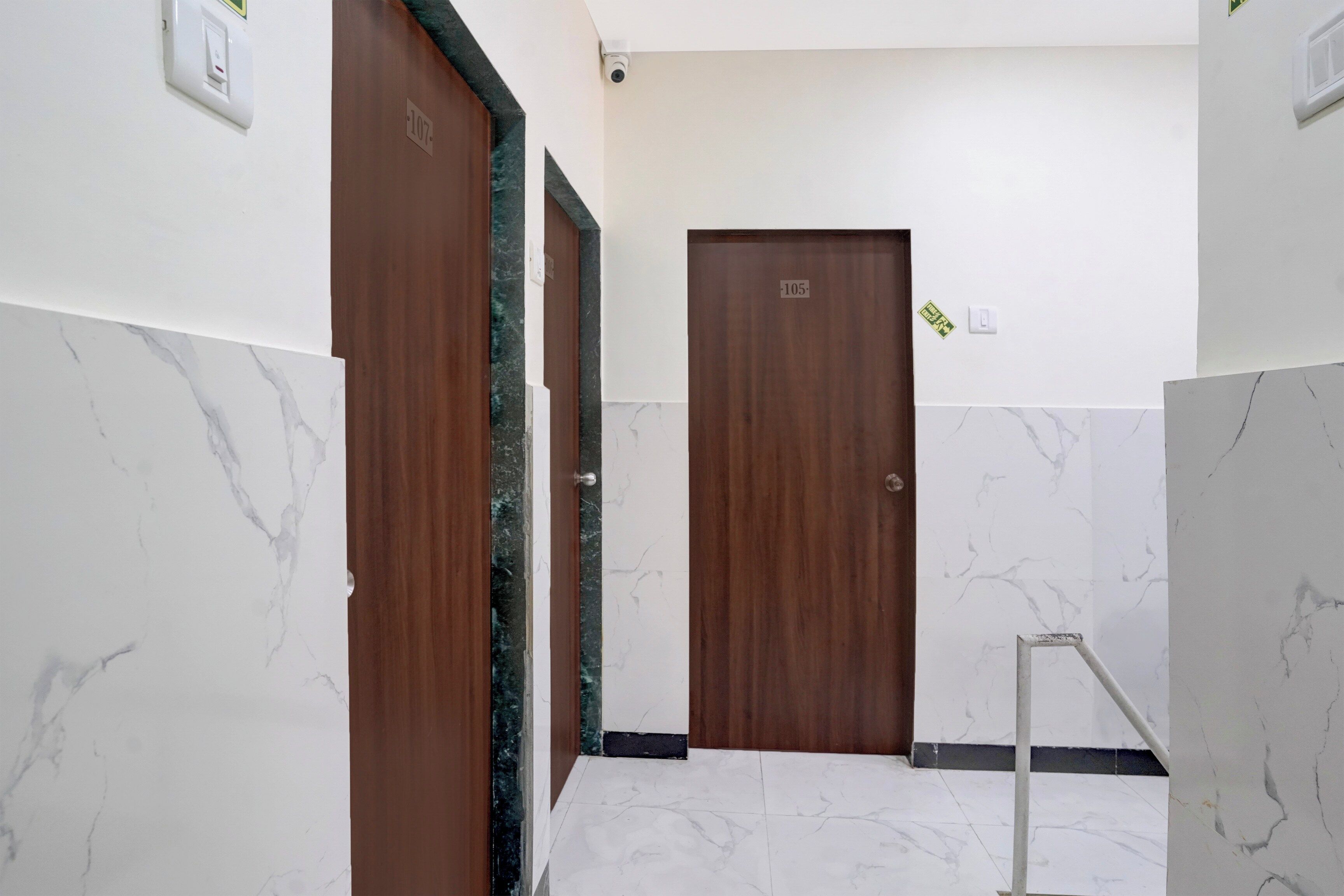 A hallway with marble walls and two wooden doors, one marked with the number 107 and the other with 105.