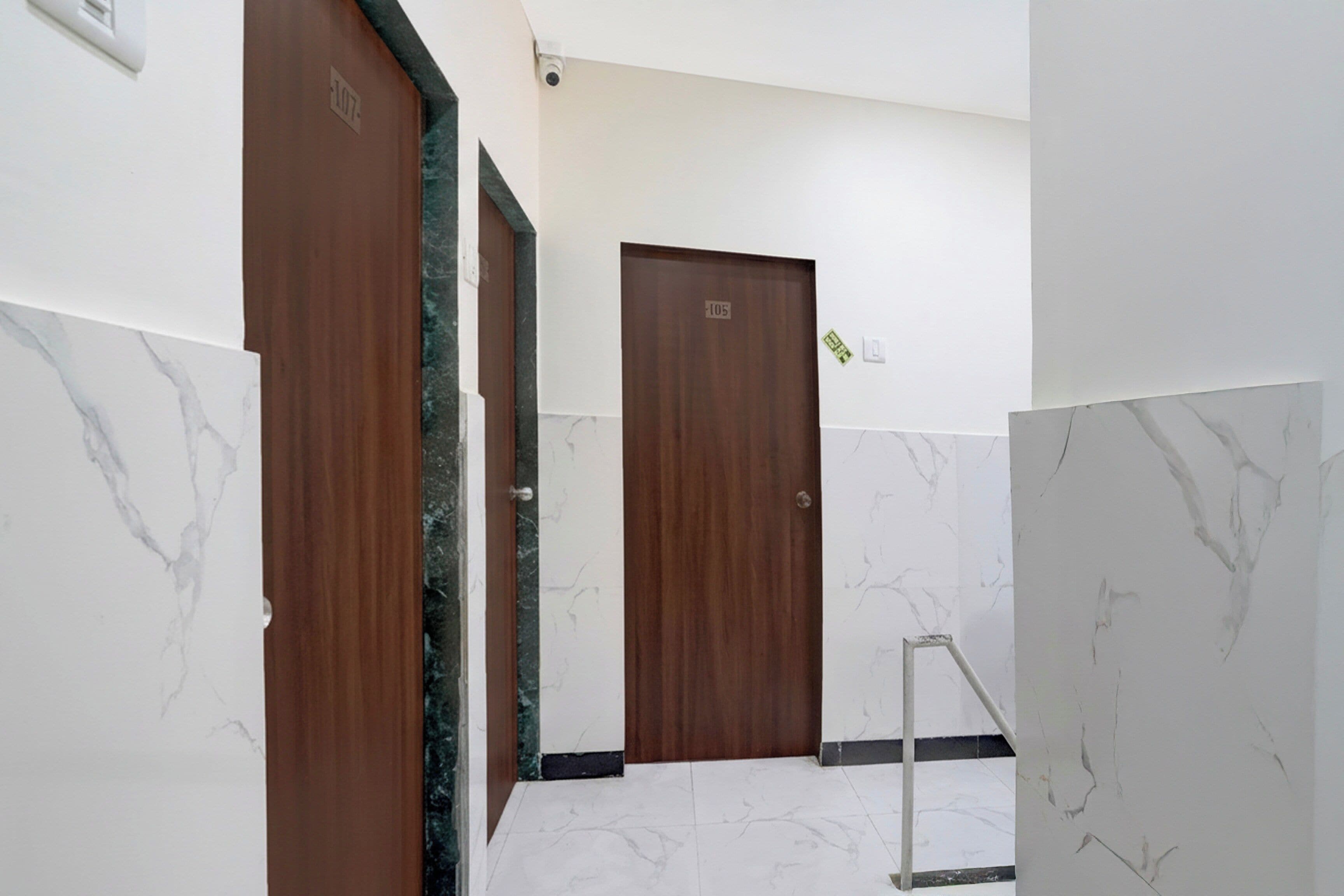 Un pasillo con suelo de mármol y puertas de madera, cada una con un número.