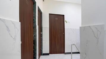 Un pasillo con suelo de mármol y puertas de madera, cada una con un número.