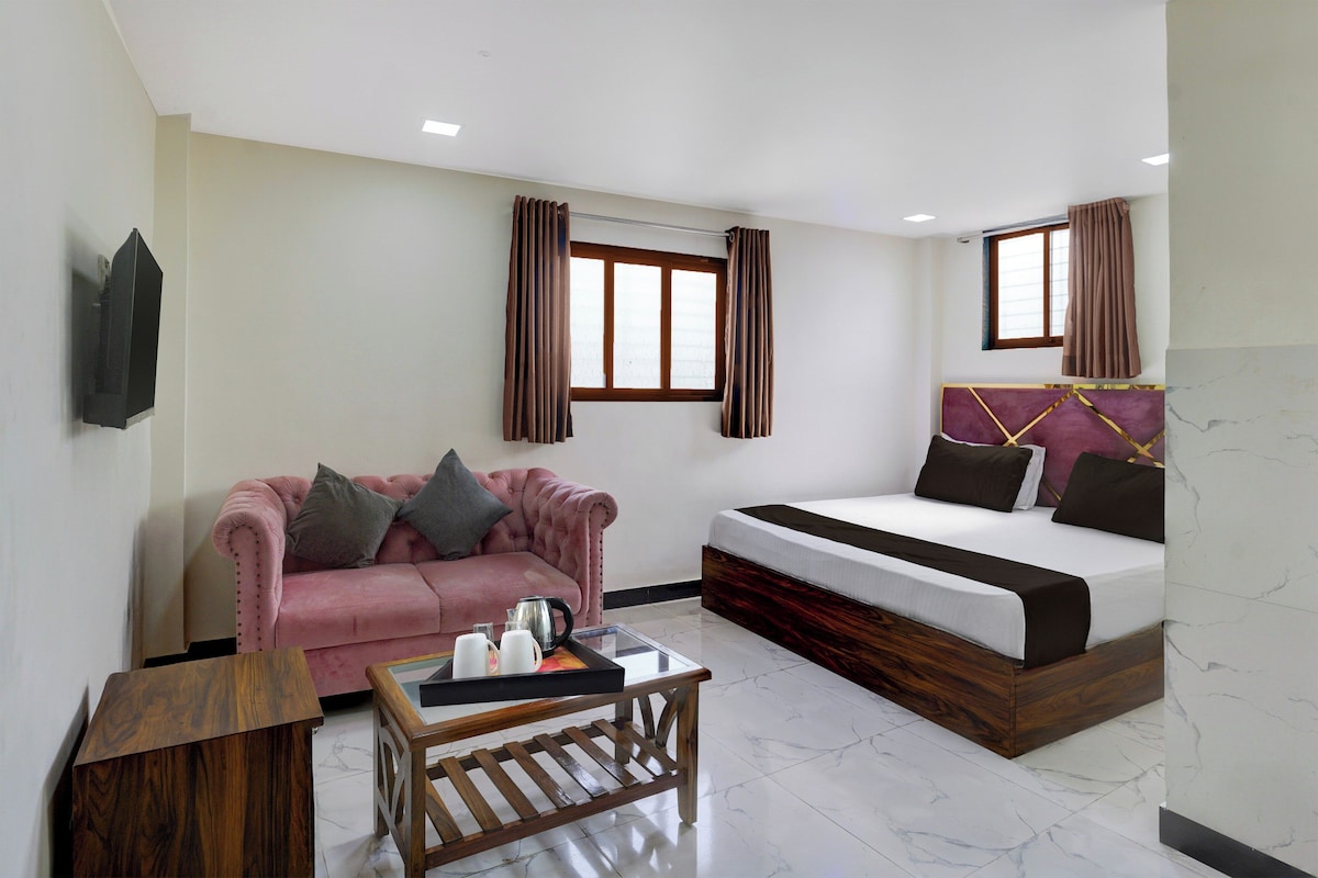 Une chambre d’hôtel compacte comprenant un lit, un canapé, une table basse et une petite table d’appoint en bois.