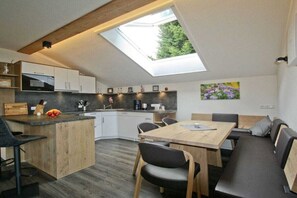 Una cucina moderna con un lucernario, una zona pranzo con tavolo e sedie in legno, e una panca integrata.