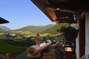 Una terrazza con un tronco di legno, posti a sedere all'aperto e un vaso di fiori sospeso.