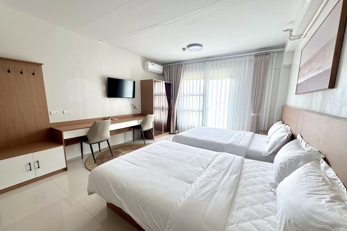 Una camera d'albergo con un letto, una scrivania, una sedia, una televisione e un armadio.