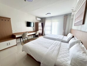 Una camera d'albergo con un letto, una scrivania, una sedia, una televisione e un armadio.
