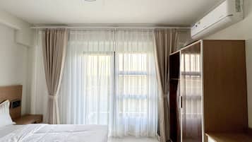 Een hotelkamer met een bed, een kledingkast, een bureau en een raam met gordijnen.