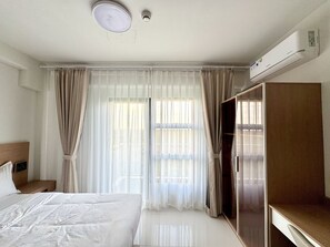 A hotel room with a bed, a wardrobe, a desk, and a window with curtains. - Royal Oceancrest Panglao 1 (Dauis)