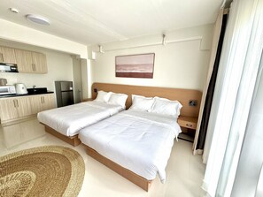 A hotel room with two beds, a kitchenette, and a view of the beach. - Royal Oceancrest Panglao 1 (Dauis)