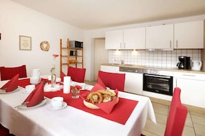 A dining area with a table set for two, white tablecloth, red napkins, and a basket of pretzels. - Dreisessel - Neukirchinger Holiday Farm (Tiefenbach)