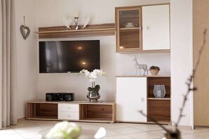 A modern living room with a flat-screen TV, wooden entertainment unit, and decorative items. - Dreisessel - Neukirchinger Holiday Farm (Tiefenbach)