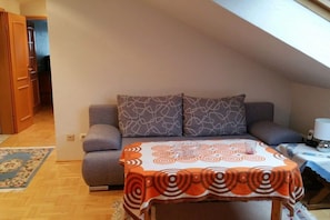 A cozy room with a sofa, a patterned tablecloth, and a small table with a lamp. - in the Spessartblick house (Kleinheubach)
