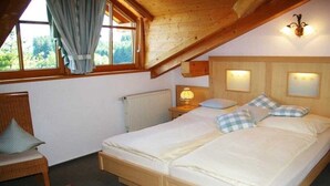 Quarto com duas camas, janela com cortinas, radiador e luminária na parede.