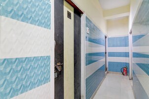 Un pasillo con paredes de diseño, una puerta con placa de número y un extintor.