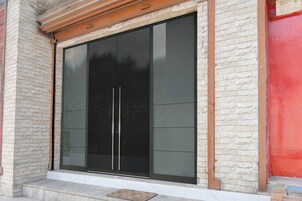 Una entrada moderna a un edificio con puerta de cristal y fachada de piedra.