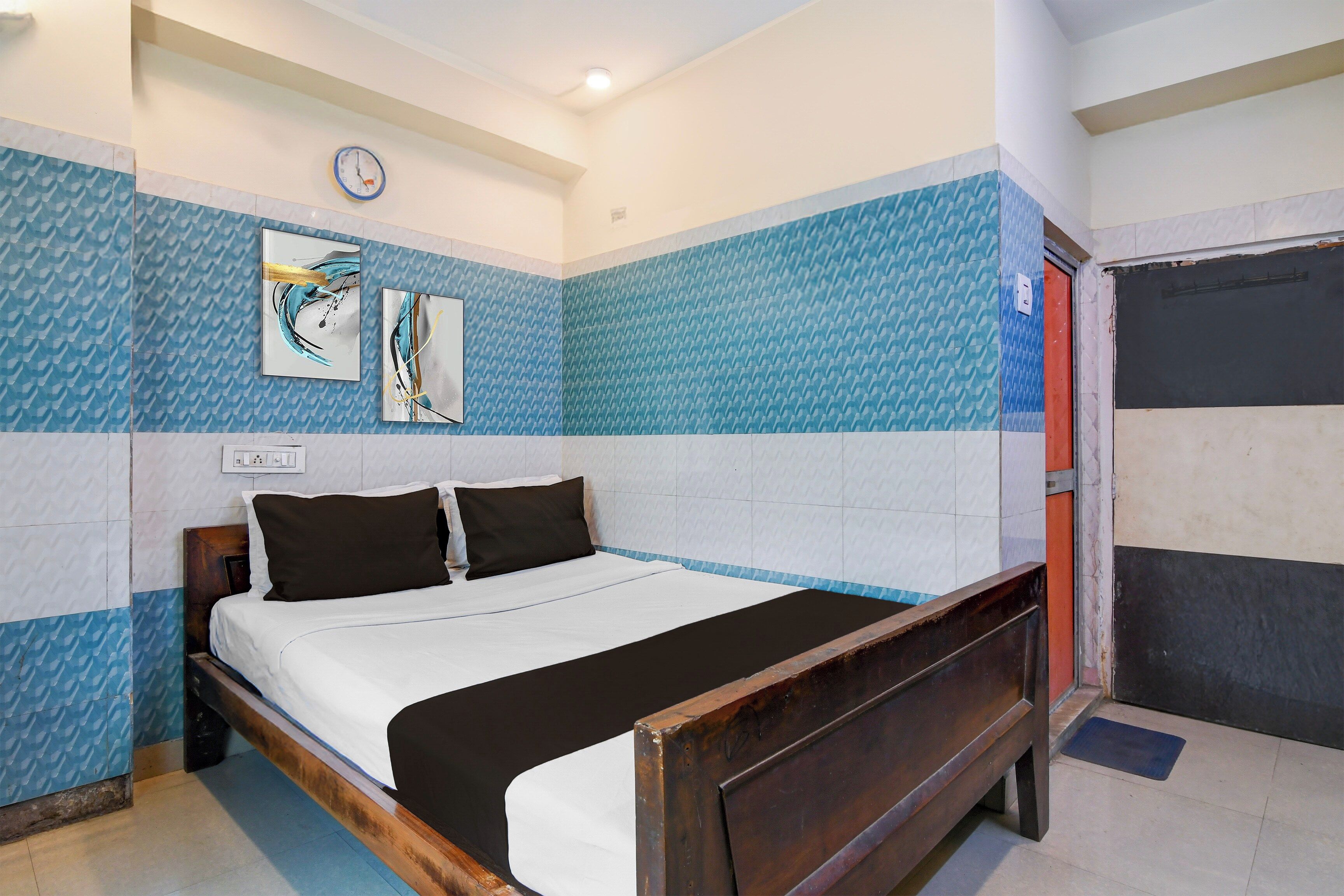 Una habitación de hotel con una cama, un reloj y dos obras de arte en la pared.