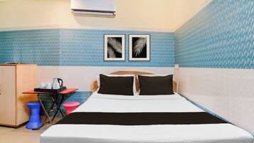 Una habitación de hotel con una cama, una mesita con un hervidor, un taburete azul y un armario.