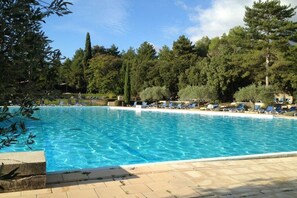Ein klares Schwimmbecken mit Liegestühlen und Bäumen im Hintergrund.