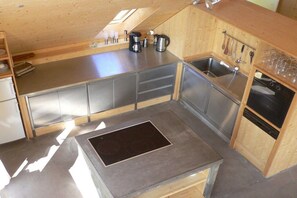 A compact kitchen with a built-in stove, stainless steel appliances, and wooden cabinetry. - Basseltang Hus - S"Denn (Todtnau)