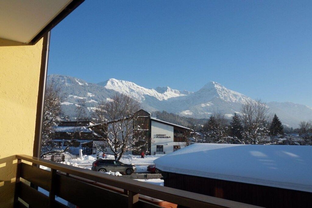 Paesaggio montano con un edificio con la scritta 'FISCHER' e terreno innevato.