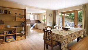 Una cocina amplia con armarios de madera, una mesa de comedor con sillas y una estantería llena de libros.
