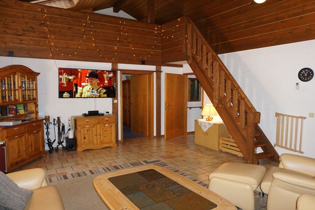 A wooden interior with a staircase, a television, and a radiator.