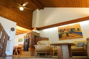 A cozy living room with a wooden ceiling, a painting on the wall, and a fireplace. - Holiday home in Zandt with swimming pool (Zandt)