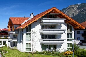 A multi-story residential building with a sloped roof, balconies, and a well-maintained lawn. - Citrine Suite ARCHDUKE GISELA (Oberstdorf)