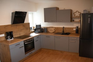 A compact kitchen with grey cabinets, a black refrigerator, and a wooden countertop. - Holiday apartment in Garmisch-Partenkirchen with swimming pool (Ga-Pa)