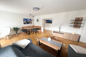 A modern living room with a sofa, coffee table, and dining area. - Holiday apartment in Garmisch-Partenkirchen with swimming pool (Ga-Pa)