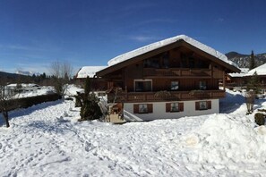 A wooden chalet with a balcony, surrounded by snow-covered ground. - Apartment with 1 bedroom (Reit im Winkl)