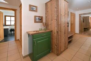 A hallway with a green cabinet, wooden paneling, and two framed pictures on the wall. - Apartment with 1 bedroom (Reit im Winkl)