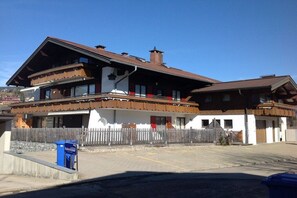 A two-story building with a wooden facade, a balcony, and a fenced area in front. - Alpenflair holiday apartment 228 (Oberstdorf)