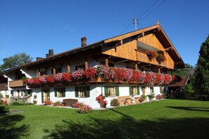 Un chalet traditionnel doté d’un toit à pente, d’un balcon en bois agrémenté de jardinières et d’une pelouse bien entretenue.