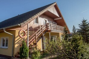 A two-story house with a balcony, a wooden staircase, and a circular window. - Holiday apartment with 1 bedroom (Karlshagen)