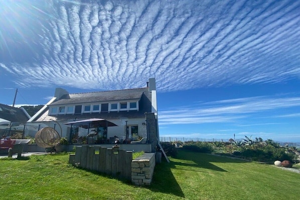Une maison dotée d’un patio, d’un mur en pierre et offrant une vue sur la mer.