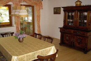 Ein Essbereich mit einem Tisch für vier Personen, einem Holzkabinett mit Glastüren und einer Pendelleuchte.