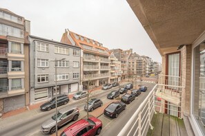 A residential street with multi-story buildings, parked cars, and a clear sky. - Central Apartment Near Rubensplein Beach (Knokke-Heist)