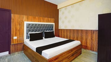 Una habitación con cabecera de madera, cama con ropa de cama negra y pared con estampado.