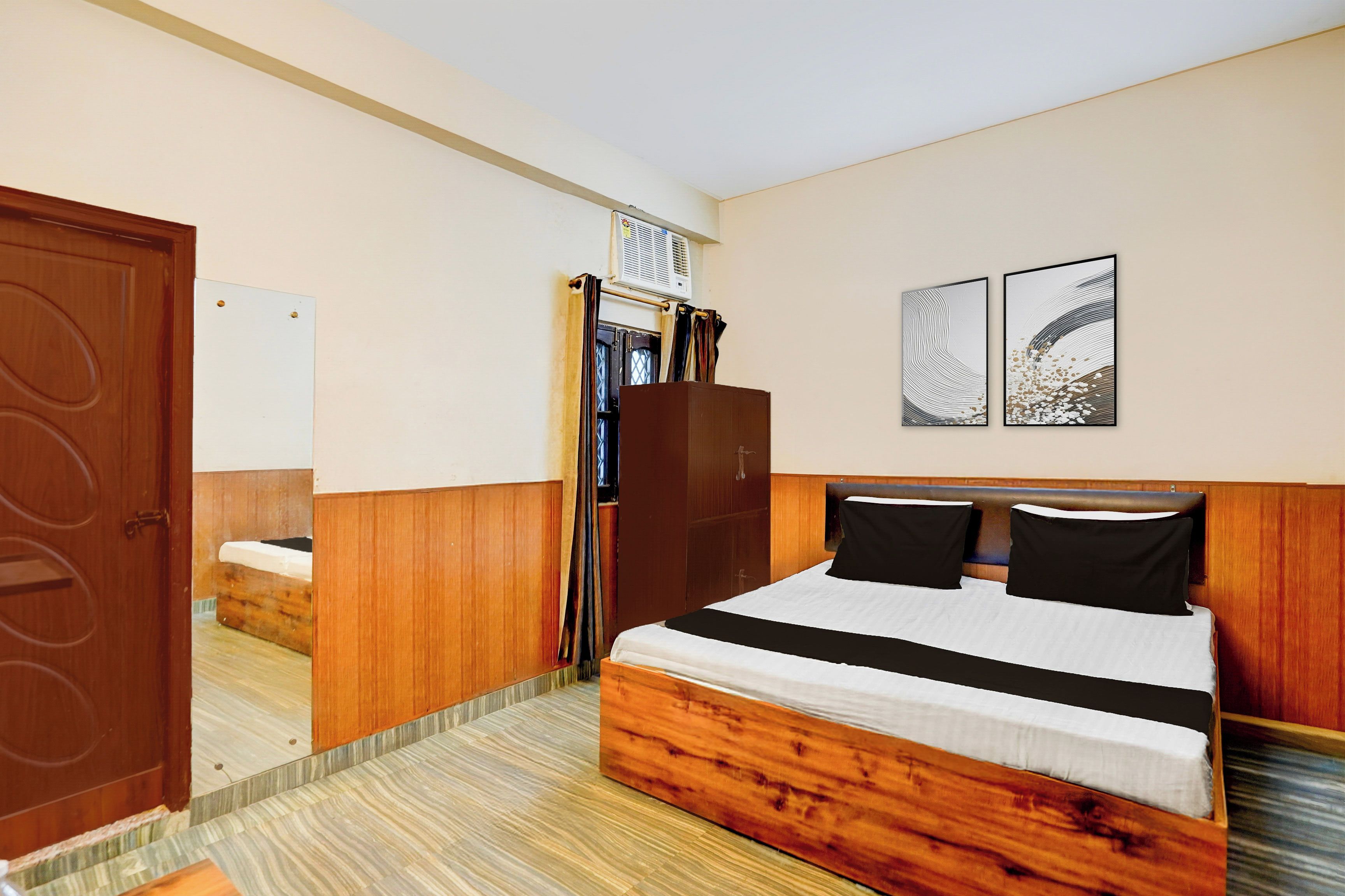 Ein Hotelzimmer mit einem hölzernen Bett, einem Kleiderschrank, einem Spiegel und zwei an der Wand befestigten Kunstwerken.