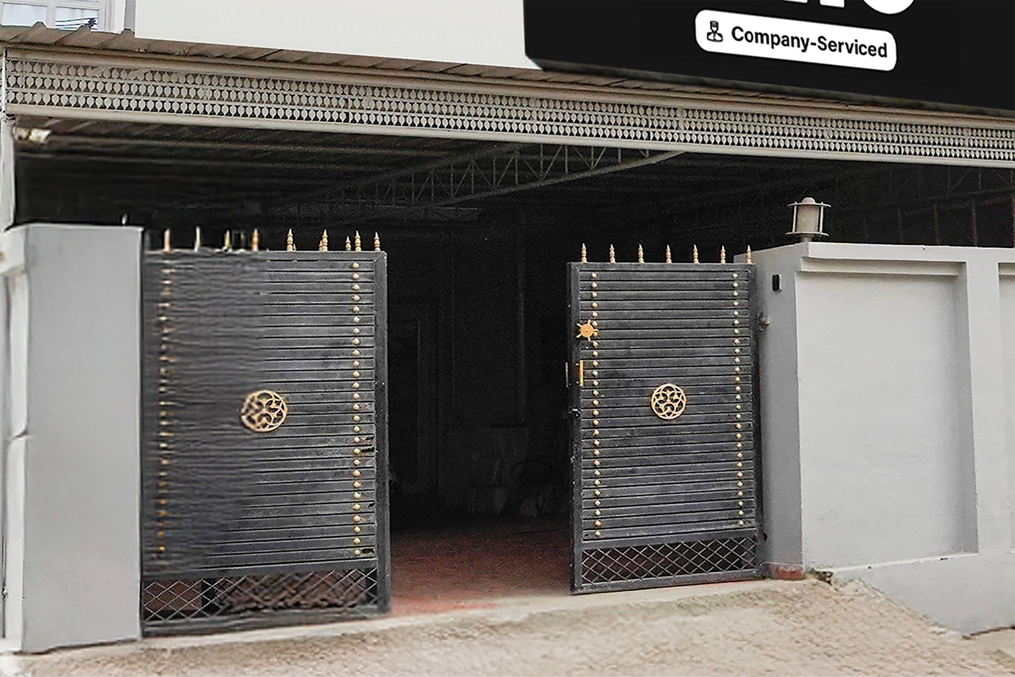 Une entrée fermée par un portail orné de grilles métalliques décoratives, avec un panneau d’identification entretenu par l’entreprise au-dessus.